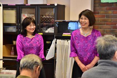 左から紫のシャツと黒のロングスカートを履いたピアノ伴奏の山下 千恵子先生と歌唱指導の豊岡 真弓先生が笑顔で立っている写真