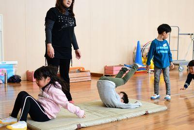体育マットの上で子供たちが順番に前周りをしている写真