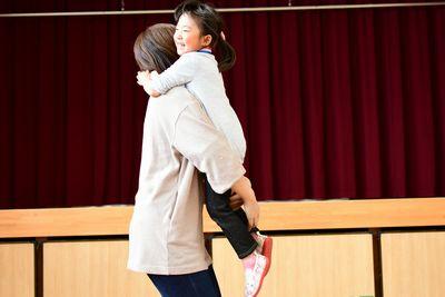 小さな女の子がお母さんに高く抱っこされて笑っている写真