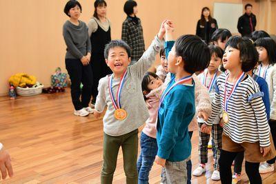 メダルをかけた男の子二人がつないだ手を高く上げている写真