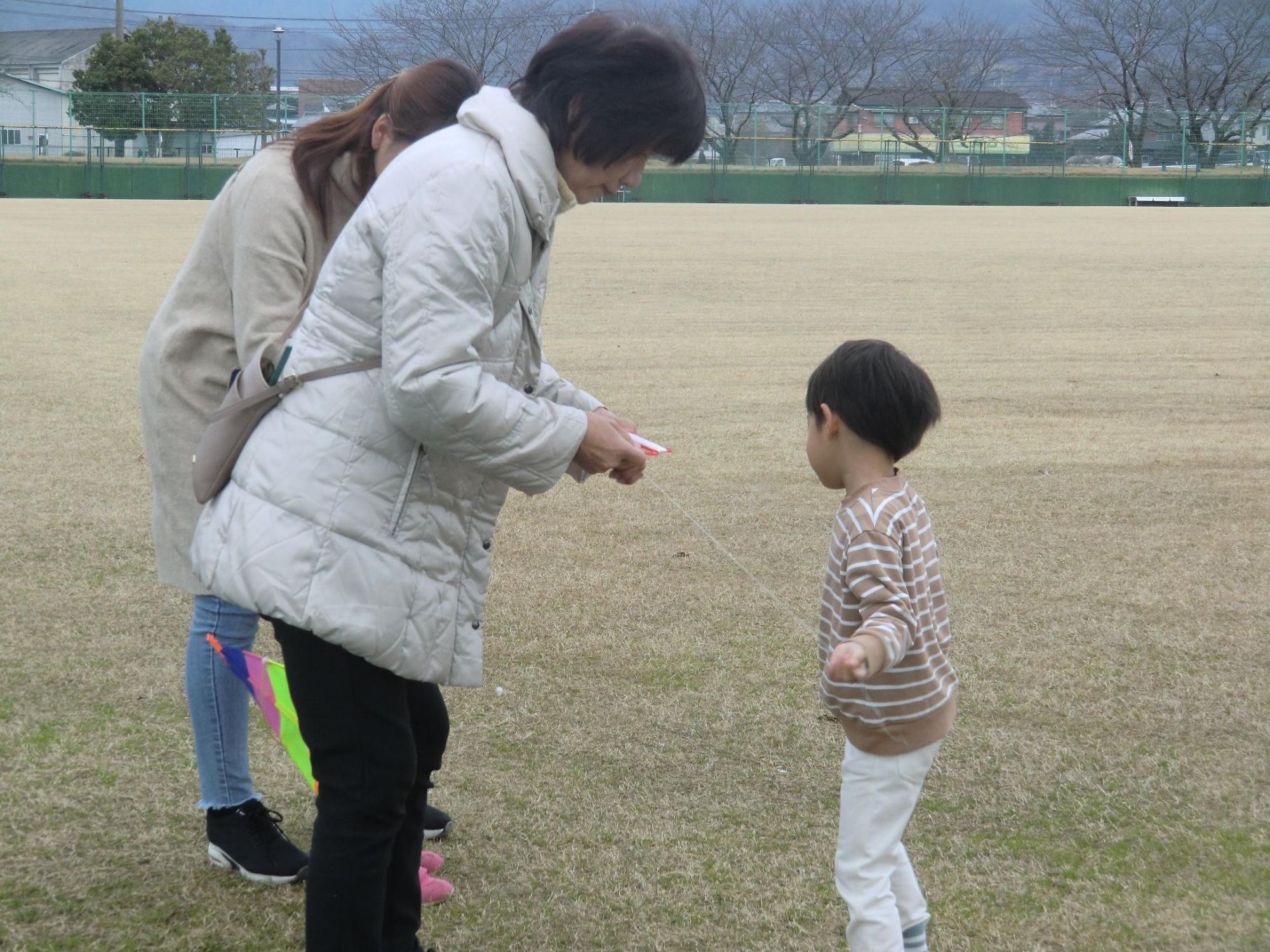 お母さん、おばあちゃんの3人でたこあげをする男の子