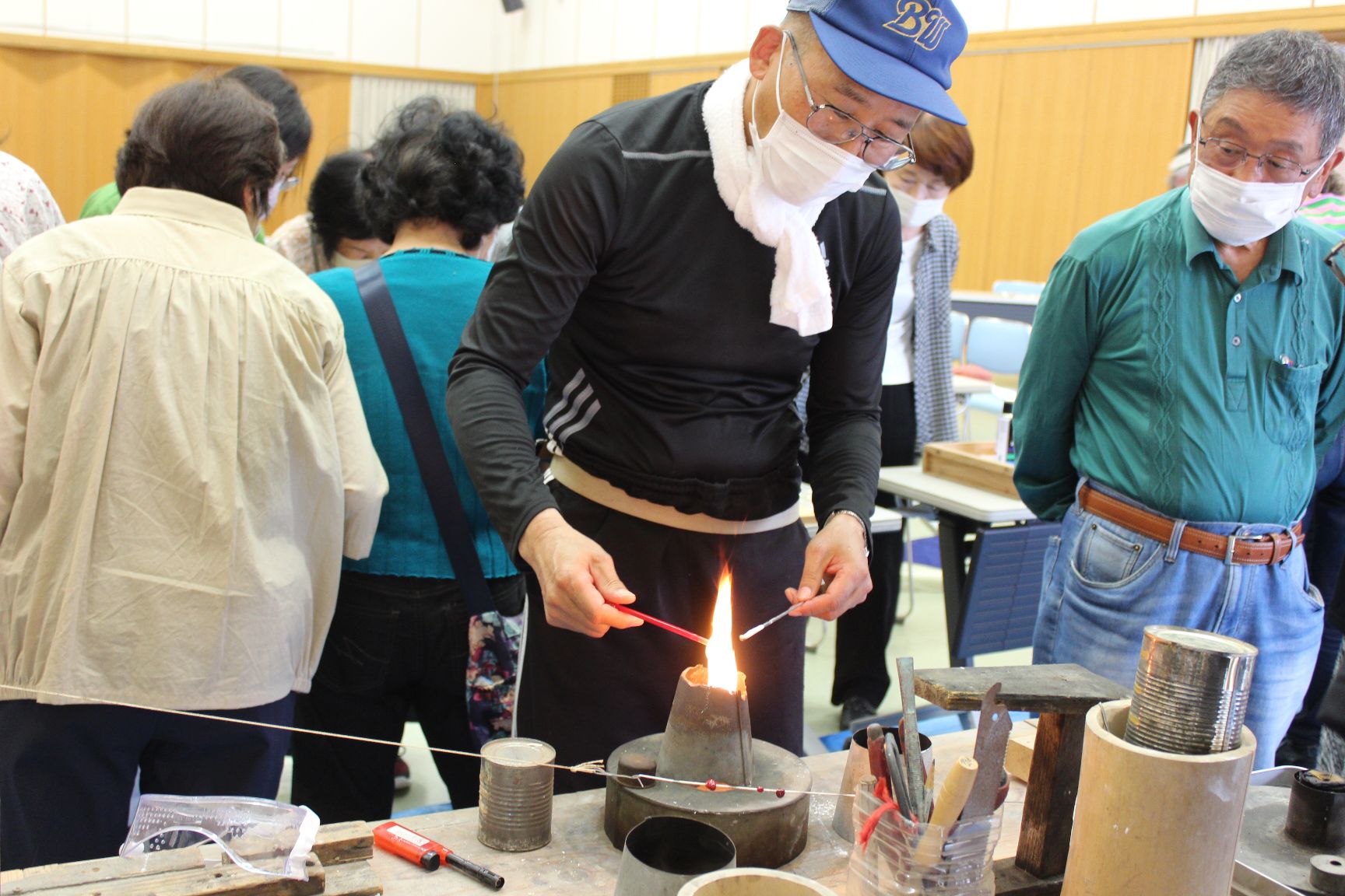 ランプの火で生地がよく溶けた所で丸く巻き付ける作業中