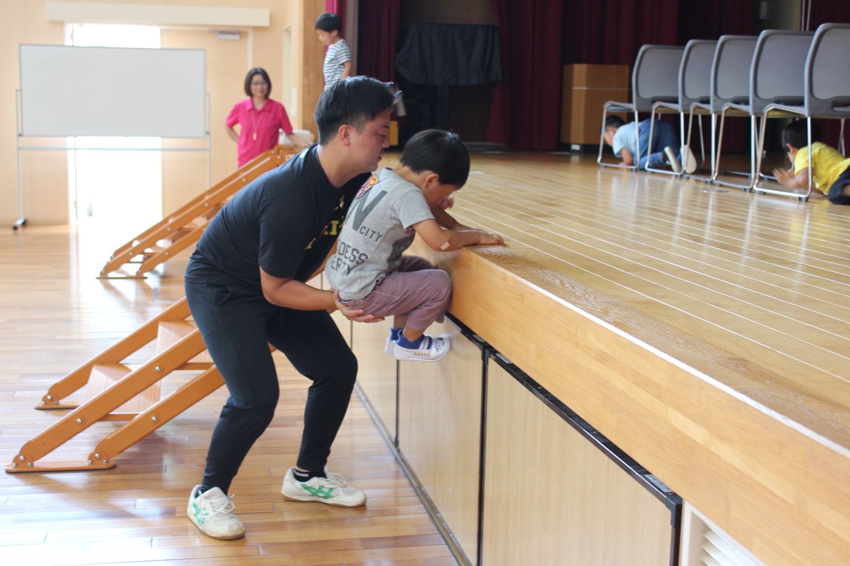 大学生のお兄さんに助けてもらいステージを登る幼児