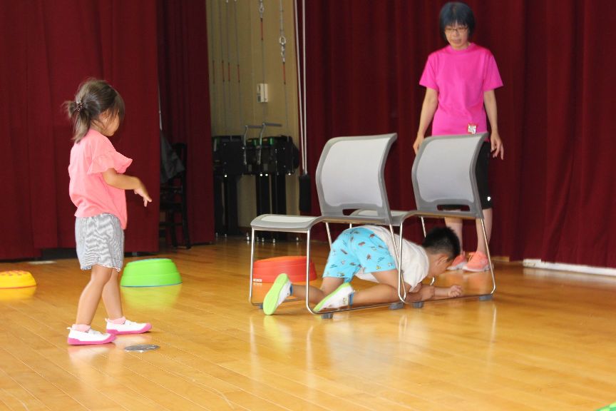 サーキット遊びの椅子の下をくぐる子ども