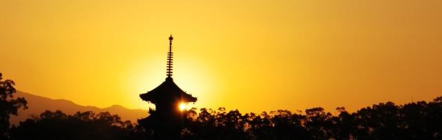 オレンジ色の夕焼けの空に浮かぶ本山寺の写真