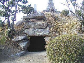 台地に石で囲まれた穴が掘ってあり、上には宝篋印塔が建てられている延命古墳の写真