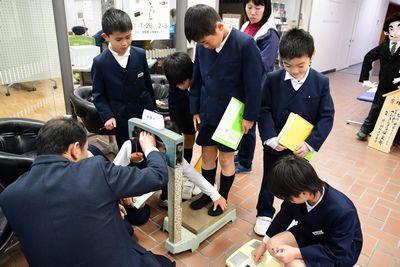 男子生徒の1人が台はかりに乗って体重を測っている写真