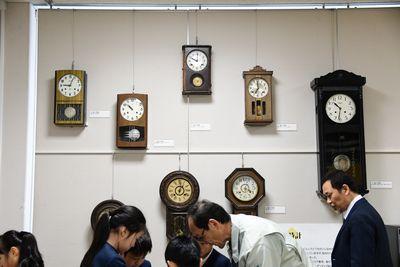壁に掛けられている7つの大小さまざまな振り子時計の写真