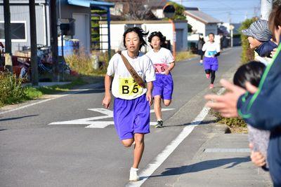 女の子のランナー3人が走り沿道の方が拍手で声援をしている写真