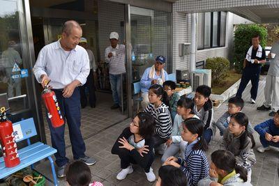 男性が消火器を持って、子供達に説明している写真