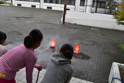 火のイラストにめがけて、子供達が水をかけている写真
