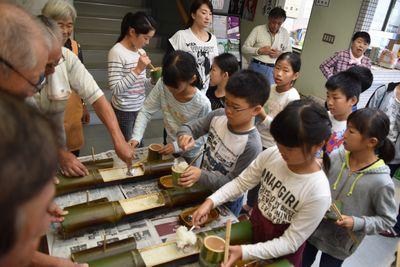 竹をの真ん中を開けて、その中に子供達がご飯を入れている写真
