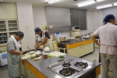 調理室で男性達がエプロンをして調理している写真