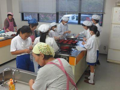調理室で子供達が白いエプロンに帽子を被り調理している写真