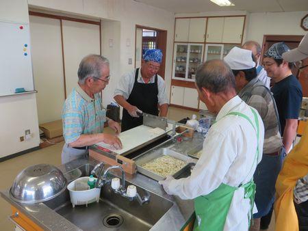 大きな包丁を男性が持って、うどんの麺を切っている写真