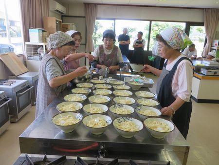 女性達が器にうどんの麺を分けて入れている写真