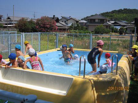 プールに入って園児たちと一緒に水遊びをしている小学生の写真
