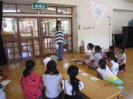 お仕事体験を終えた9人の小学生の女の子の前に立って話をしている所長さんの写真