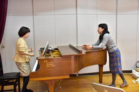 ピアノ伴奏の牧野 玲子さんと有家 真理さんがピアノ越しに話をしている写真