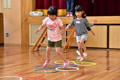 床に置かれたリングの中を跳んでいる女の子たちの写真