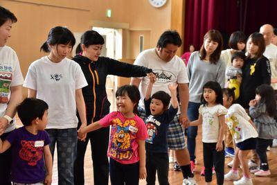 保護者と子供たちが手をつないで列を作っている写真
