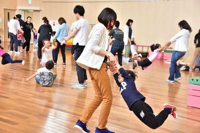 保護者が子供の手を握りグルグルと回っている写真