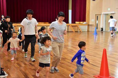 保護者と子供たちが一緒に体育館の中を走っている写真