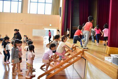 子供たちが順番に階段の前に並んで壇上に上がっている写真