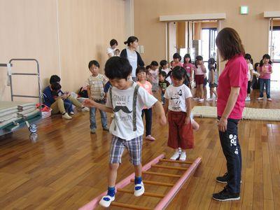 床に置かれたピンク色のはしごの上を男の子が歩いている写真