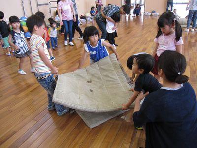 半分に折られた体育マットを子供たちが運ぼうとしている写真
