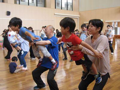 子供たちがお父さんやお母さんの太ももの上に背を向けて立ち飛行機のポーズをしている写真