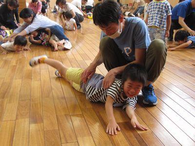 床にうつ伏せになっている子供たちの背中を触っている保護者たちの写真