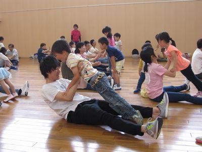 床に座っている保護者が、子供たちを両手で持ちあげようとしている写真