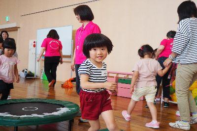 トランポリンが置かれている前をストライブのティーシャツを着た女の子が笑顔で駆け出し来ている写真