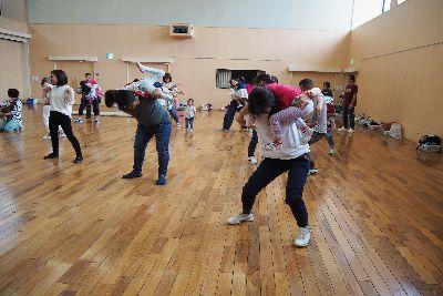 親子ペアで会場に広がっており、親が足を開いて構えており、子どもが親の体をよじ登っている写真