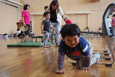 椅子が繋がって置かれており、椅子の脚の間を、男の子が四つん這いになって、くぐって出てきている写真