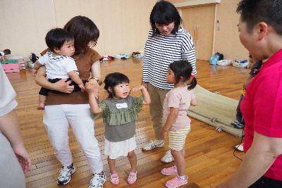 赤ちゃんを抱っこしたお母さんと手を繋いでいる女の子が、スタッフの女性と向かい合って話をしている写真