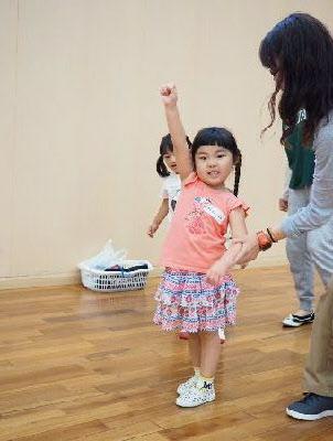 右手の拳を上にあげて立っている女の子と、女の子の左腕を持つお母さんの写真