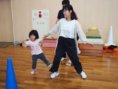 手をつないで、足を大きく開いた体勢のおかあさんと、片手でピースをしてカニさん歩きのようなことをしている女の子の写真