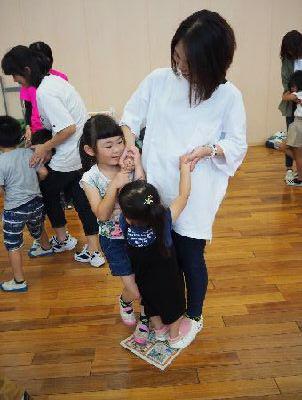 床の上に小さく折りたたまれた新聞紙の上に立つ、お母さんと、女の子2人の写真