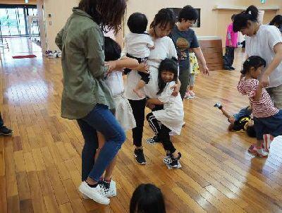 片足立ちのお母さんの足の上に、抱きつきながら立つ子供たちの写真