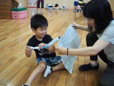 親子が、新聞紙を破っている写真