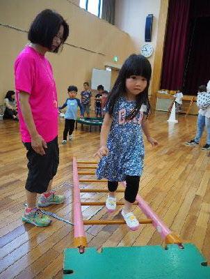 木のはしごを渡る髪の長い女の子の写真