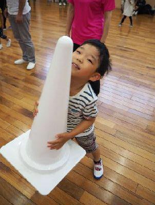 白いカラーコーンを運ぶ男の子の写真