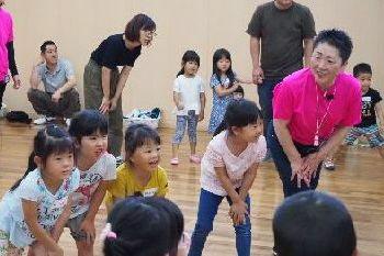 前に出した足の上に両手を置いている体勢の女性スタッフや、子供たちの写真