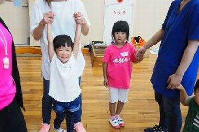 お母さんに両手を持ち上げられている笑顔の女の子の写真