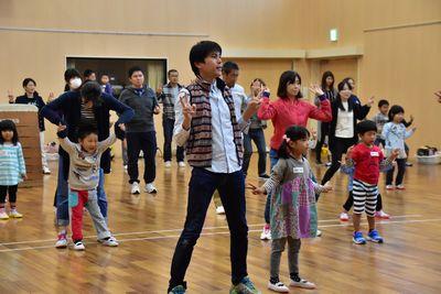 参加者の親子たちが両手でピースを作りカニ歩きのポーズをしている写真