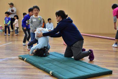 マットの上で女の子が前転をするのを女性スタッフが補助している写真