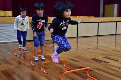 オレンジの遊具が等間隔に置かれていて、その上を子供たちがジャンプしている写真