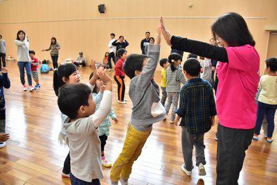 子どもたちが順番に女性スタッフと両手でハイタッチをしている写真